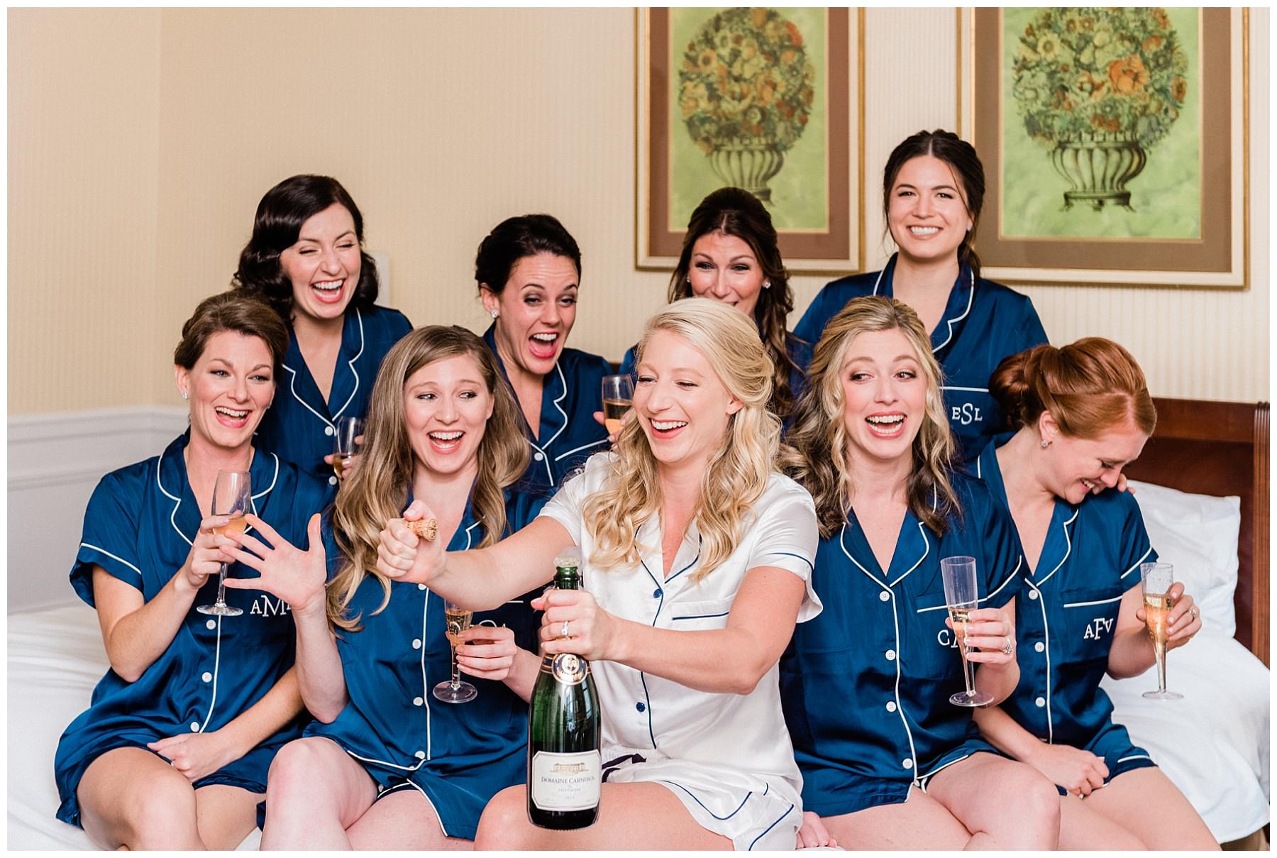 bride popping a champagne with her bridesmaids while sitting on a bed at the drake hotel in chicago